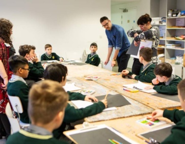 Group of children sitting around a table working on drawings optimized