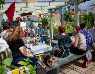 Group of people sitting around a table in a garden chatting