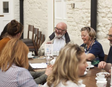Group of people sitting at a table chatting and laughing