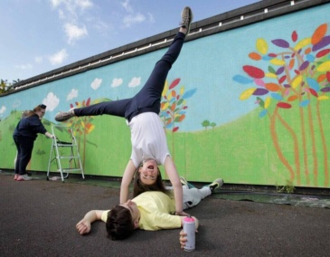Student doing cartwheel in front of mural