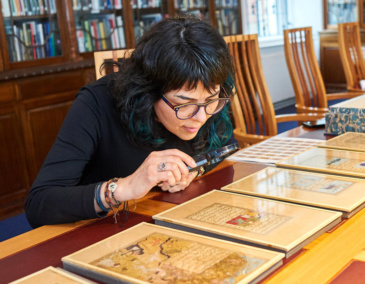 Woman looking at a manuscript with a magnifying glass at the Chester Beatty