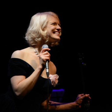 Emilie Conway on stage with microphone in hand