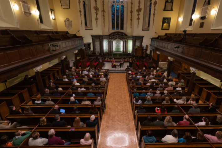 Decorative dublin festival of history 2025 an audience listen to the great irish wives writers talking in a large church 800x540