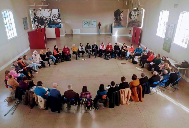 Decorative A group of Culture Company staff sit in a large circle at a team meeting 800x540