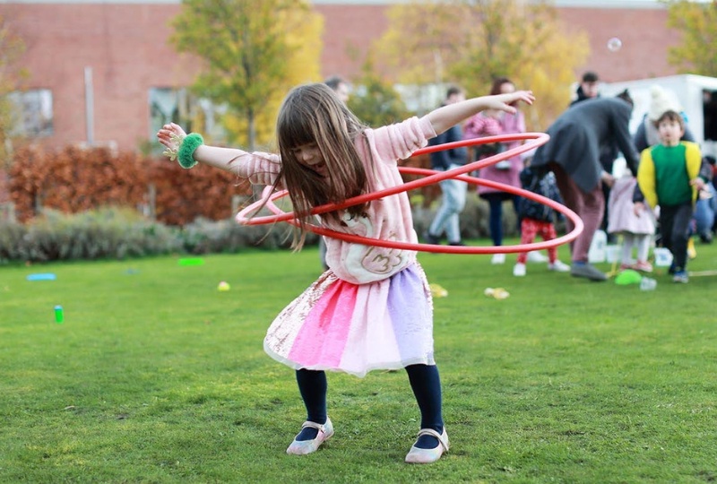 Decorative a little girl wears two hula hoops as she plays in the Richmond Barracks garden 800x540
