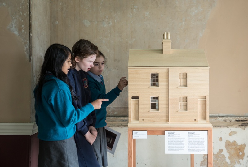 Decorative three schoolgirls look at a model of a house in 14 Henrietta Street 800x540