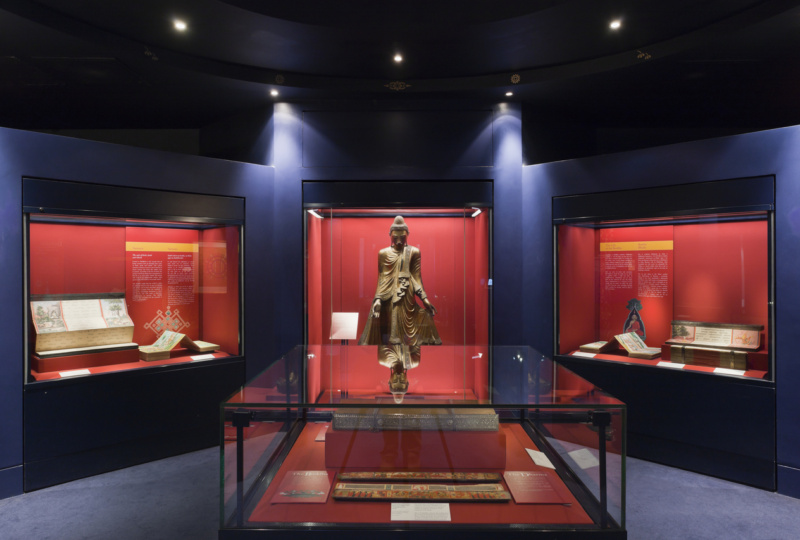 Darkly lit exhibition room in Chester Beatty with a buddha at the centre