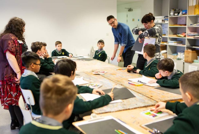 Group of children sitting around a table working on drawings optimized