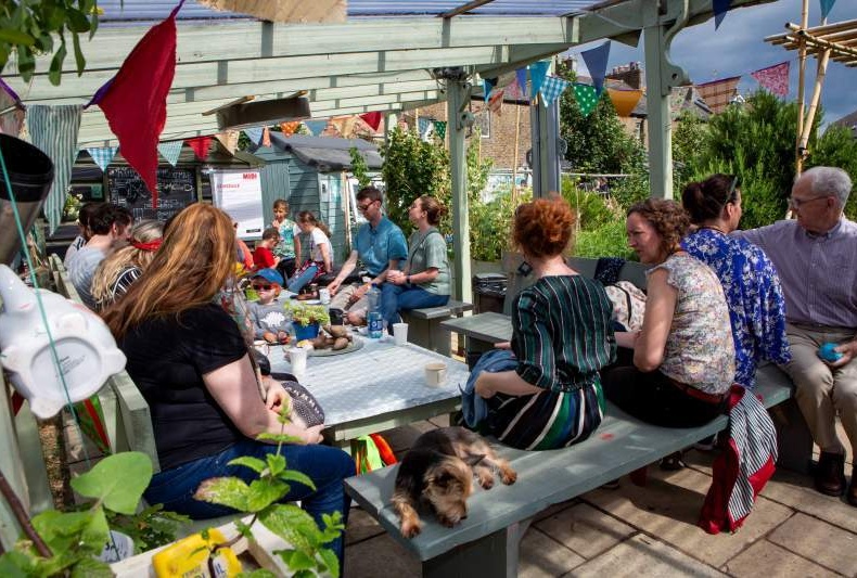 Group of people sitting around a table in a garden chatting
