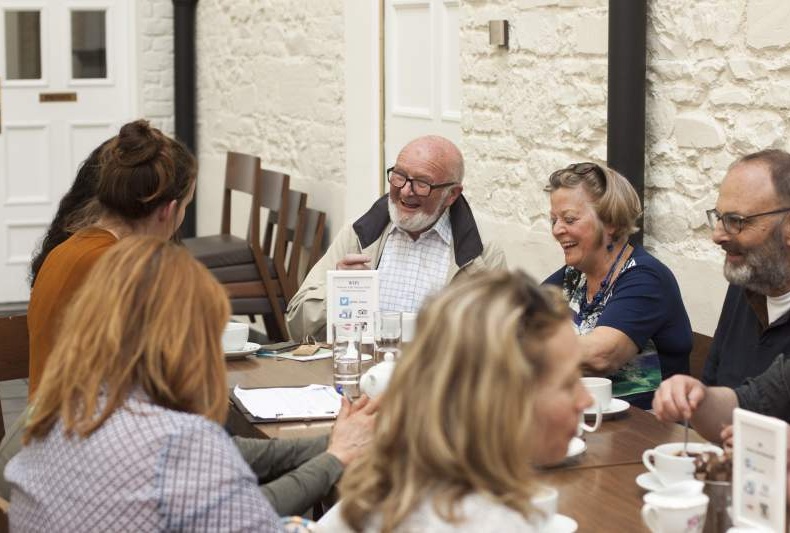 Group of people sitting at a table chatting and laughing