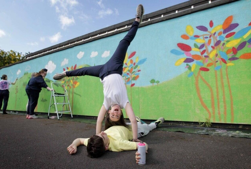 Student doing cartwheel in front of mural