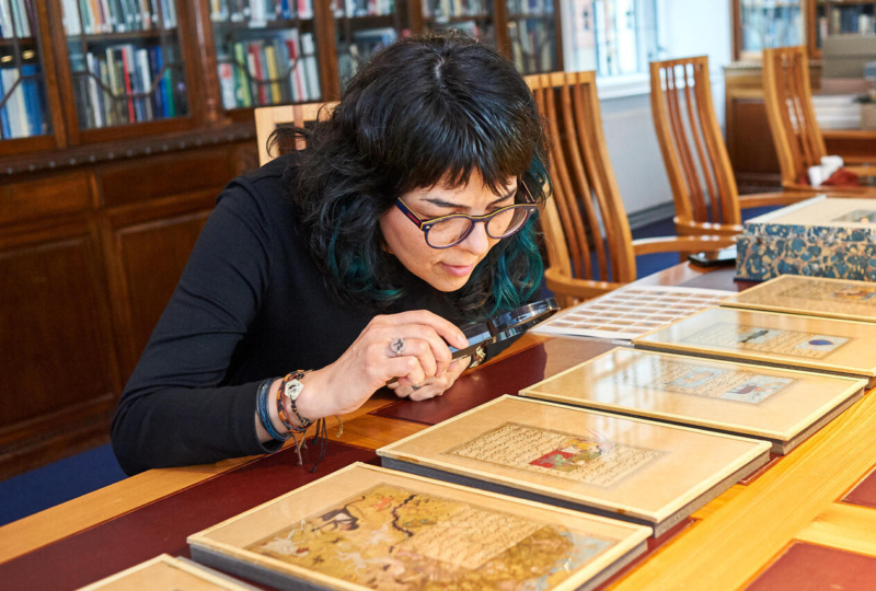 Woman looking at a manuscript with a magnifying glass at the Chester Beatty